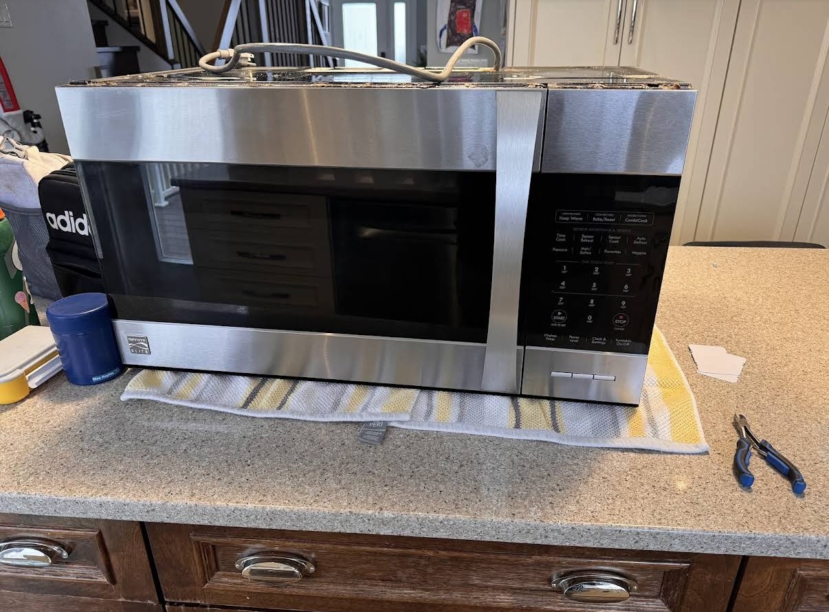 Certified technician repairing a microwave in an Oakville home